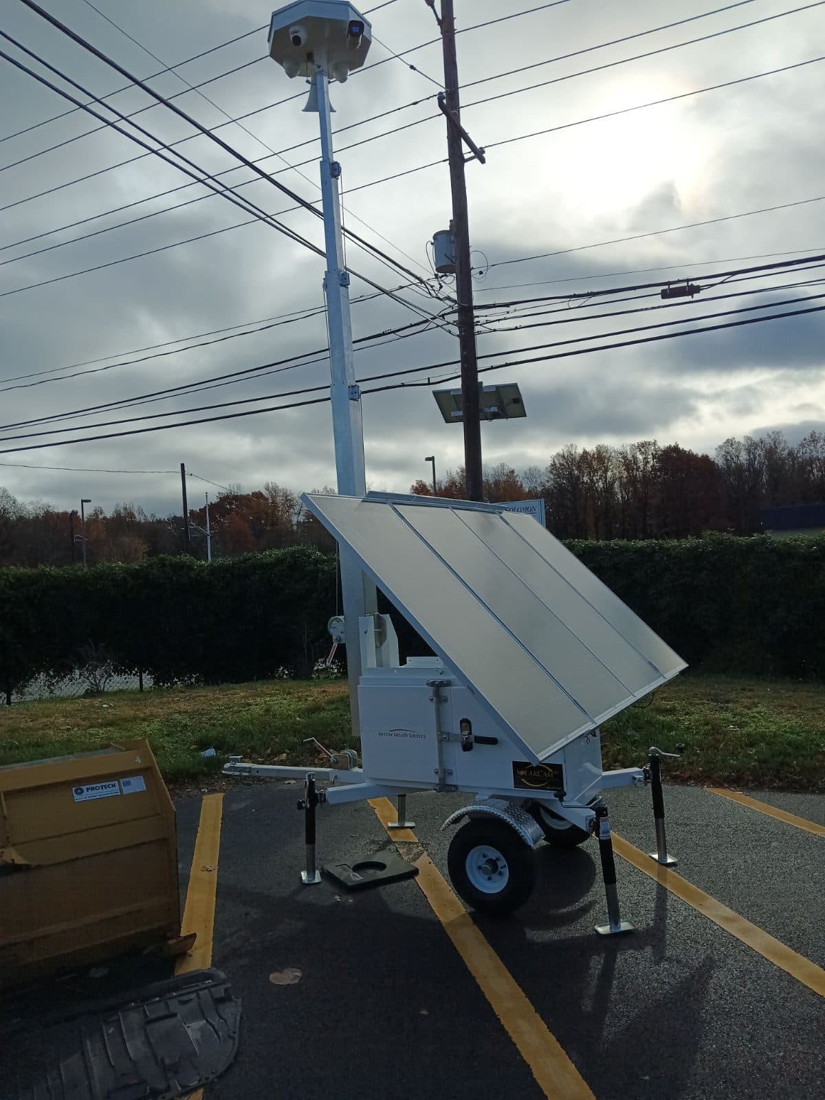 SolarCam360 solar surveillance unit deployed on a parking lot under an overcast fall sky