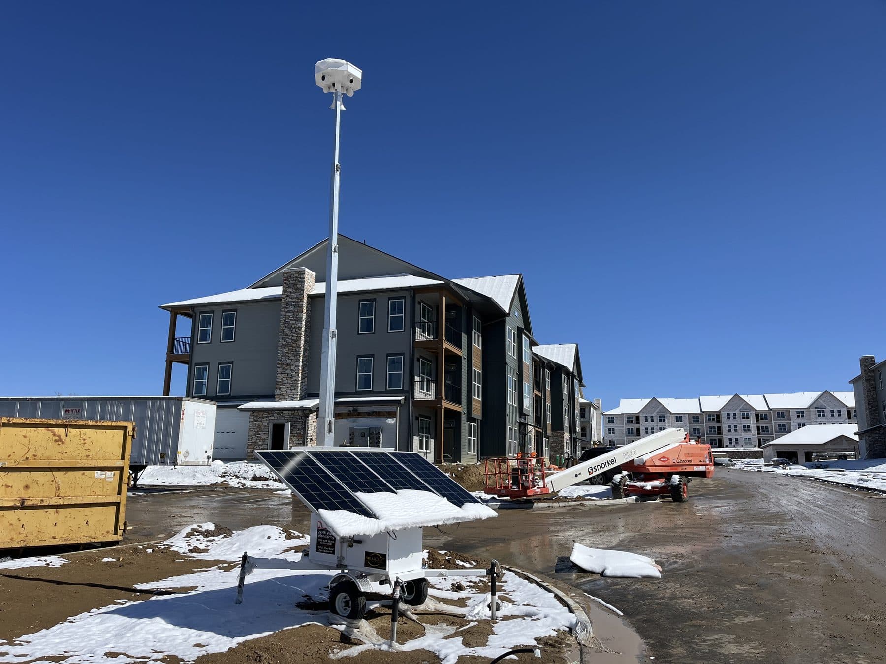 SolarCam360 solar surveillance unit with snow on its panels at a multifamily construction site